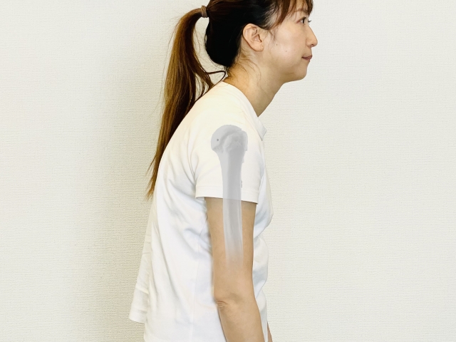 デスクワークで巻き肩になり、肩が前に出ている姿勢の女性